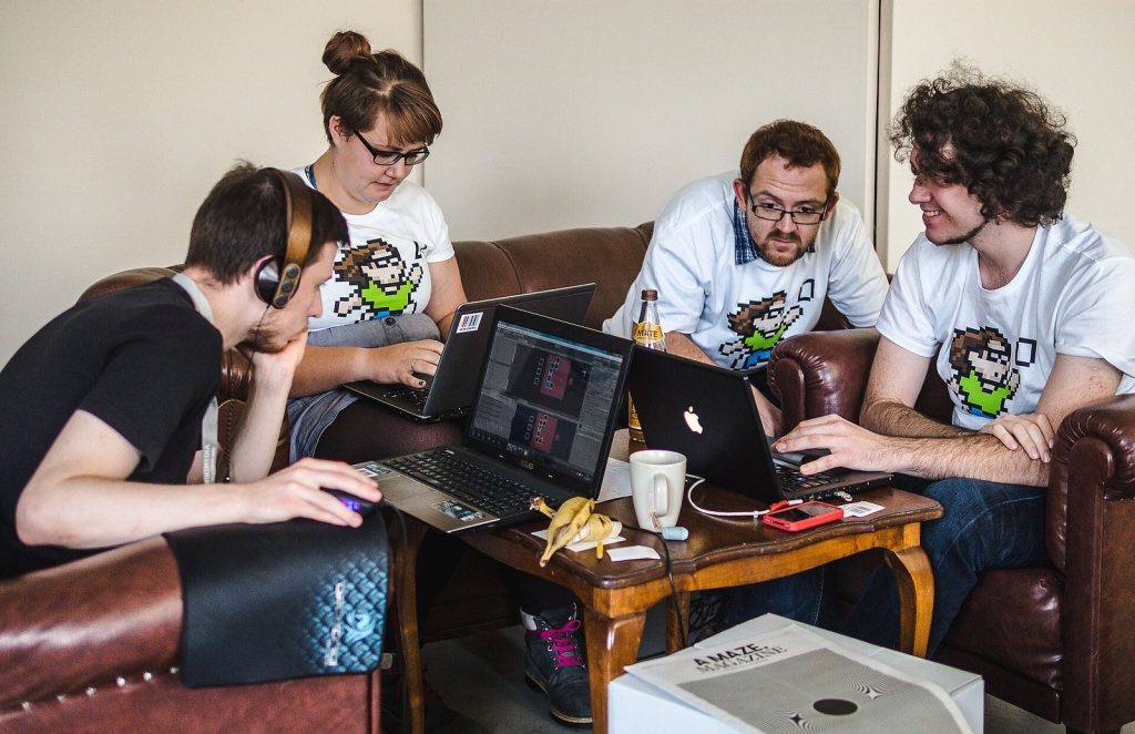 Game jam participants working together around laptops