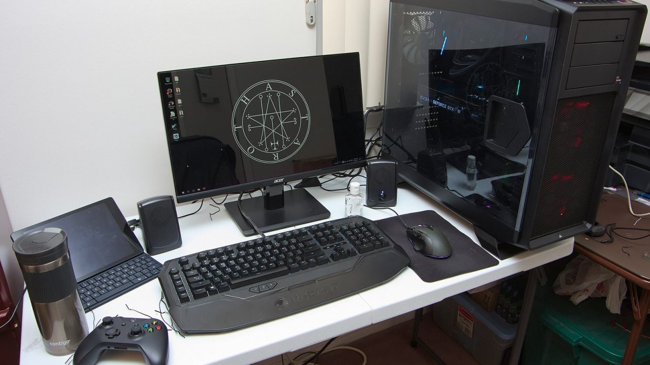 Gaming PC desk setup with monitor, keyboard and illuminated tower